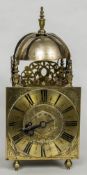 A brass lantern clock The square engraved dial with Roman numerals, alarm dial,