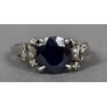 An Edwardian unmarked 18 ct white gold diamond and sapphire ring The central facet cut sapphire