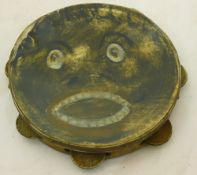 A vintage tambourine painted with a face