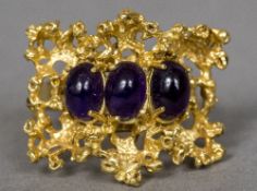 A contemporary 18 ct gold ring Of pierced form set with three cabochon amethysts. 2 cm high.