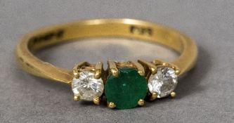 An 18 ct gold diamond and emerald three stone ring The central emerald flanked by twin diamonds.
