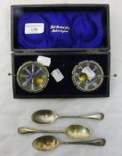 A pair of cased silver mounted cut glass salts and spoons and three silver teaspoons