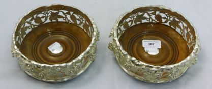 A pair of silver plated coasters with cast grape decorations