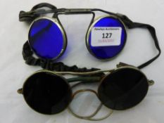 A pair of motoring tinted glasses and another pair with blue lenses