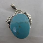 A silver and turquoise pendant