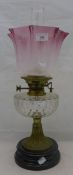 A Victorian brass oil lamp with clear glass reservoir and cranberry glass shade