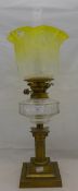 A Victorian brass oil lamp with clear glass reservoir and yellow glass shade
