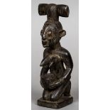 An African carved wooden tribal figure Formed as a kneeling woman holding a bowl and wearing a