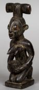 An African carved wooden tribal figure Formed as a kneeling woman holding a bowl and wearing a