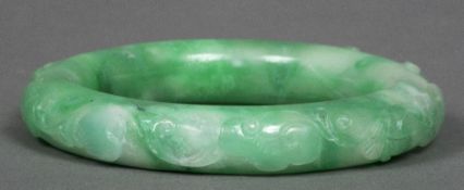 Two Chinese jade bangles One carved with scrolling foliate designs.