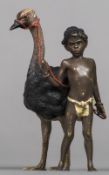 A cold painted bronze figural group Formed as a Negro boy leading an ostrich,