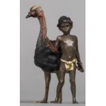 A cold painted bronze figural group Formed as a Negro boy leading an ostrich,