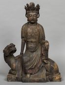 A Chinese carved wood figure of Guanyin Worked seated on a mythical beast. 54 cm high.