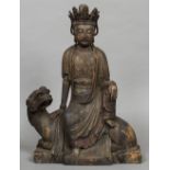 A Chinese carved wood figure of Guanyin Worked seated on a mythical beast. 54 cm high.