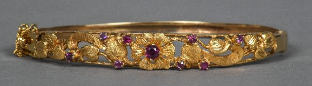 An Edwardian 9 ct gold bangle form bracelet With pierced scrolling floral design set with red