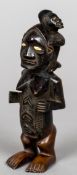 An African carved wooden tribal figure Of a woman with scarified belly and a child on her back,