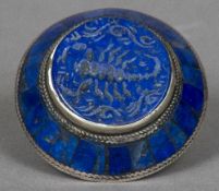 An unmarked white metal lapis lazuli set sea ring Of domed form centred with a carving of a