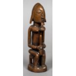 An African carved wooden tribal figure Modelled as a male figure with breasts. 24 cm high.