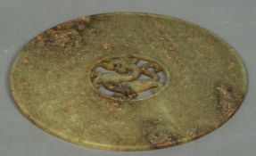 A Chinese carved green and russet jade bi disc The centre pierced and carved with a dragon.