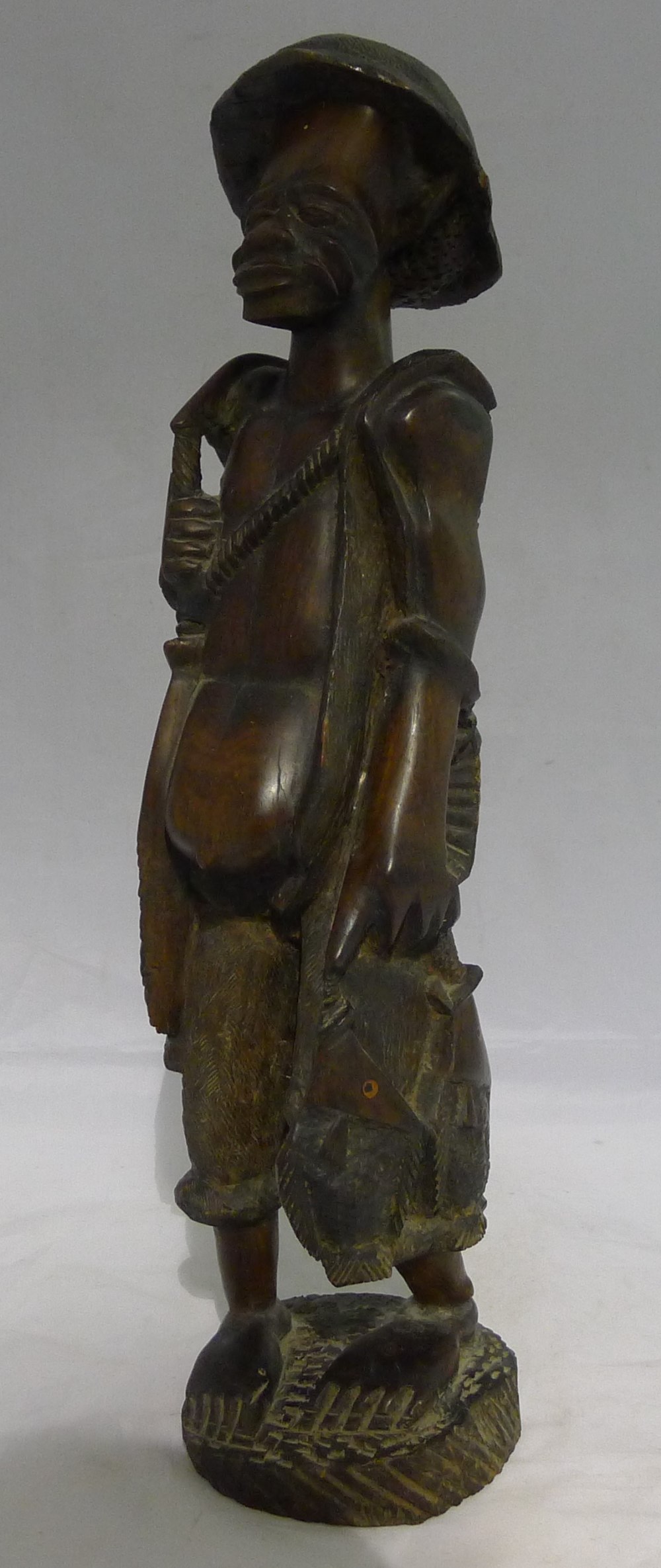 An African "tribal" carved hardwood figure of a fisherman holding his catch 48 cm high.