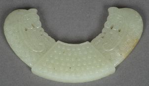 A Chinese carved celadon jade Huang pendant Worked with a pair of dragon masks issuing from a