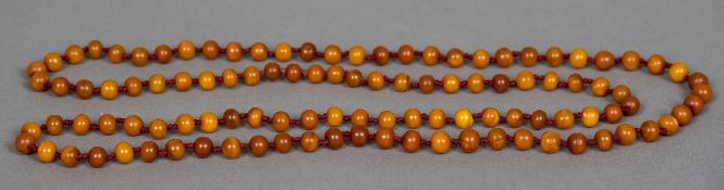 An amber bead necklace 68 cm long, the beads approximately 1 cm diameter.