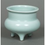 A small Chinese celadon ground censor Of typical squat circular form with three short legs,