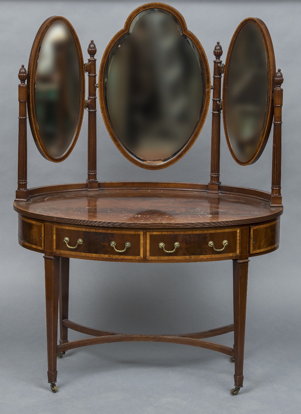 An Edwardian mahogany dressing table Of crossbanded oval form with three bevelled mirrors above two