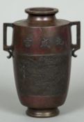 A Chinese patinated bronze twin handled vase The front decorated with pagodas amongst a mountainous