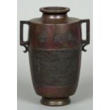 A Chinese patinated bronze twin handled vase The front decorated with pagodas amongst a mountainous