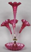 A Victorian cranberry glass epergne Of typical form, the base with wavy rim. 59.5 cm high.