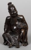 A Chinese carved hardwood figure of a sage Worked seated holding a flower. 18.5 cm high.