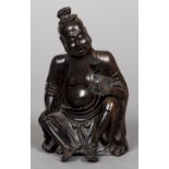 A Chinese carved hardwood figure of a sage Worked seated holding a flower. 18.5 cm high.