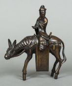 A Chinese patinated bronze censor Formed as a scholar holding a scroll and riding a donkey.