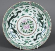 A Chinese famille verte dish Centred with flowering sprays bordered by twin dragons chasing flaming