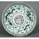 A Chinese famille verte dish Centred with flowering sprays bordered by twin dragons chasing flaming