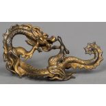 A 19th century Chinese gilt bronze brush rest Formed as a scrolling dragon. 16.5 cm wide.