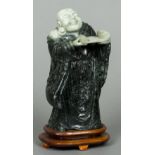 A carved jade figure of Buddha Modelled standing holding an open scroll,