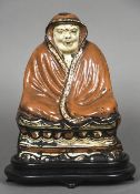 An antique Chinese pottery figure Modelled seated wrapped in a red ground robe,