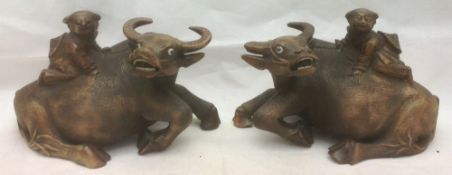 A pair of Japanese carved hardwood water buffalo Each surmounted with the figure of a child.