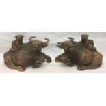 A pair of Japanese carved hardwood water buffalo Each surmounted with the figure of a child.