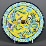 A Chinese porcelain roundel The blue and yellow ground centred with a dragon and a phoenix,