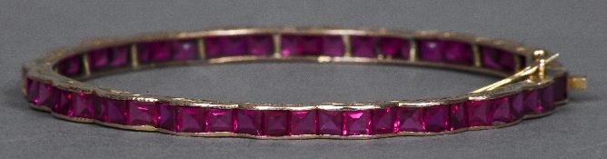 An Edwardian 9 ct gold ruby set bracelet Of lobed shaped bangle form. 7.75 cm diameter.