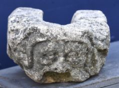 An antique carved stone gargoyle Carved with a mask, the drainage aperture forming the mouth.