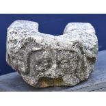 An antique carved stone gargoyle Carved with a mask, the drainage aperture forming the mouth.