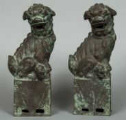 Two Chinese patinated bronze dogs-of-fo Each typically modelled seated. Each 35 cm high.