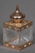 An Amouage metal mounted cut crystal scent bottle Of square section with domed removable lid.