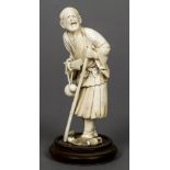 A 19th century Japanese ivory okimono Formed as a male figure holding a stick and a fan with a