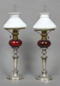 A matched pair of silver plated and cranberry glass oil lamps, the burners by F T Sale,