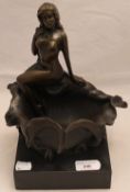 A bronze model of a nude girl seated on a shell